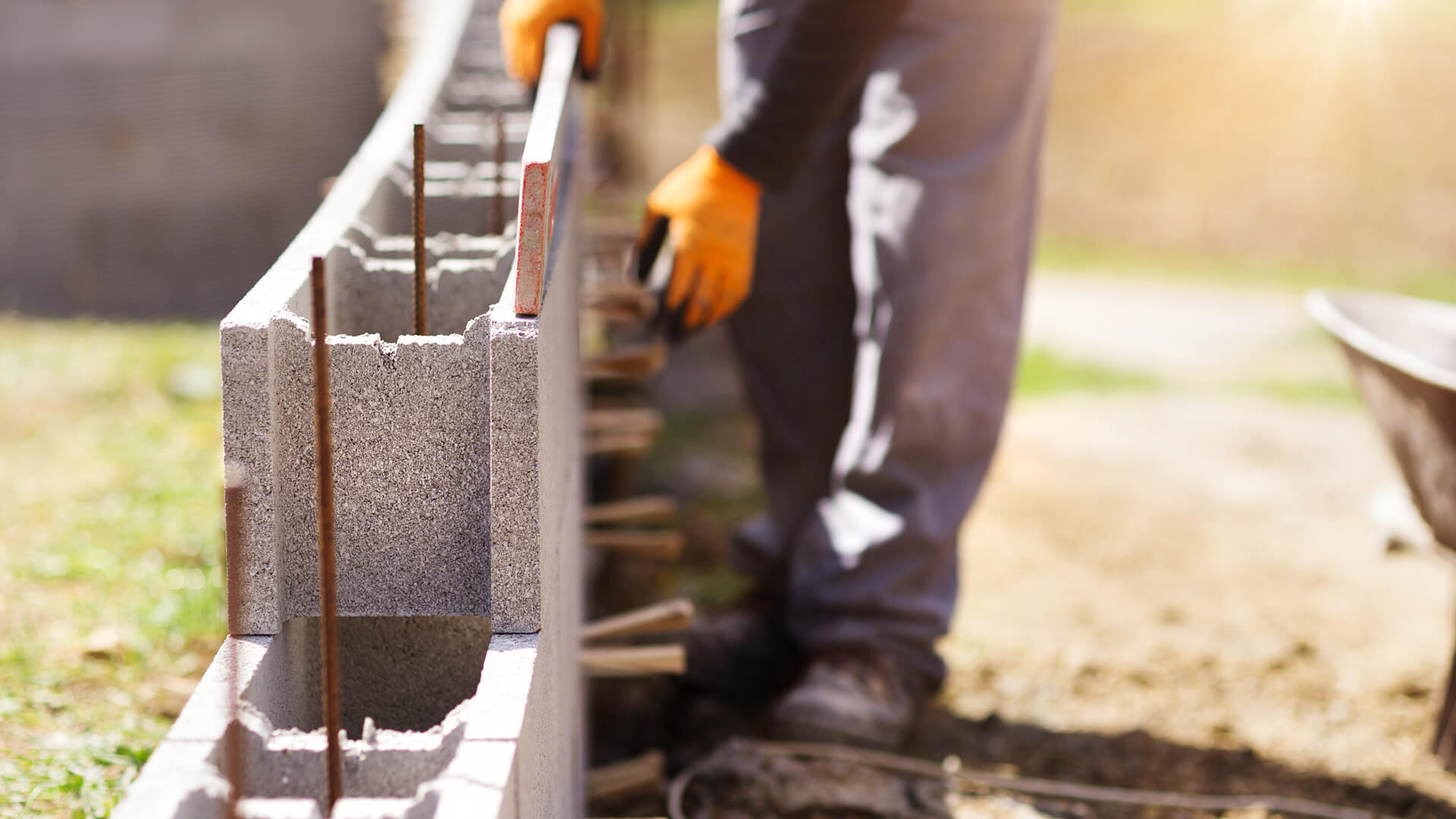 Arbeiter, der gerade eine Mauer aus Betonsteinen errichtet